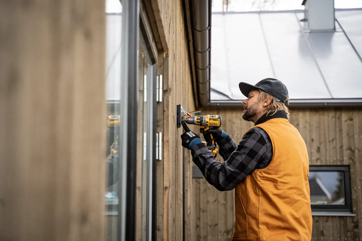 Vakman met boormachine aan het werk aan een houten gevel